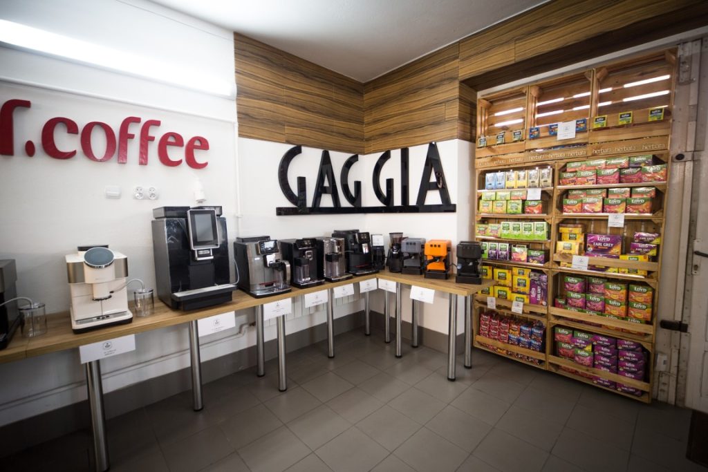 Ekspozycja ekspresów Gaggia obok regału z kawą
